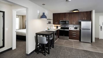 A modern kitchen with dark wooden cabinets, stainless steel appliances, and a bar area with stools.