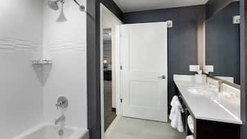 A modern bathroom with a bathtub, a shower, and a vanity with a mirror.