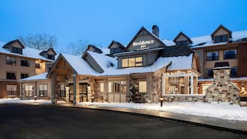 Un hôtel portant l’enseigne « Residence Inn by Marriott », avec une façade en pierre et en bois, de nombreuses fenêtres et de la neige sur le toit.