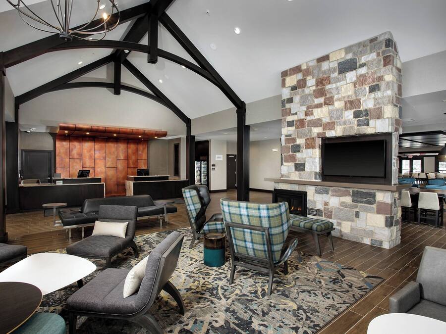 A spacious living area with modern furniture, a stone fireplace, and a kitchen in the background.