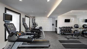 Une salle de sport équipée de tapis de course, d’un vélo d’appartement et d’un téléviseur fixé au mur.