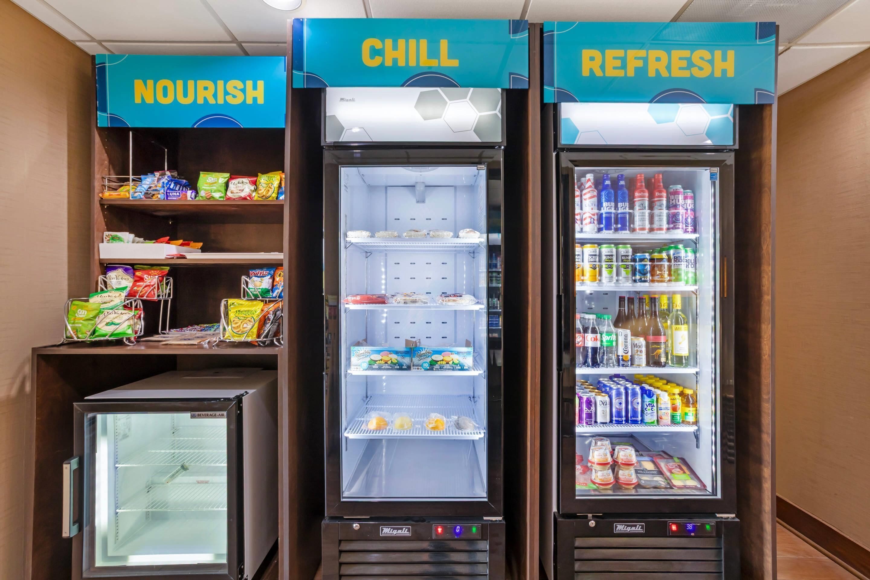 Tres dispensadores de bebidas con las etiquetas 'NOURISH', 'CHILL' y 'REFRESH', que contienen diferentes aperitivos y bebidas.