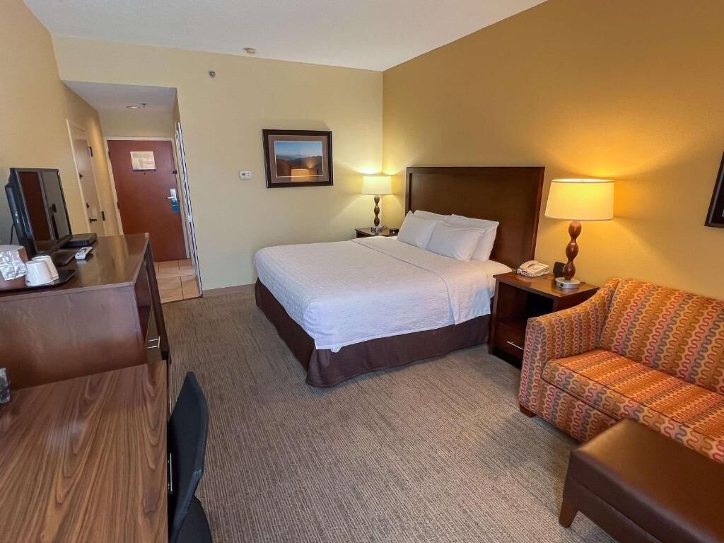 Ein Hotelzimmer mit Bett, Nachttischen, Schreibtisch, Stuhl und einer Couch.