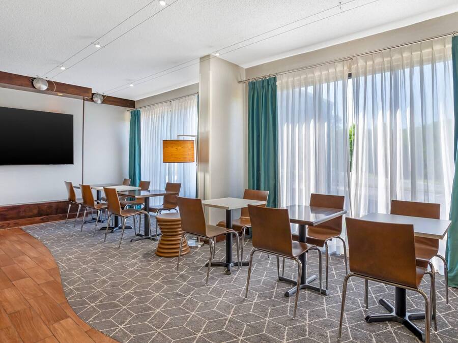 Une salle de conférence équipée d’un grand téléviseur à écran plat, de tables, de chaises et d’un tapis à motifs.