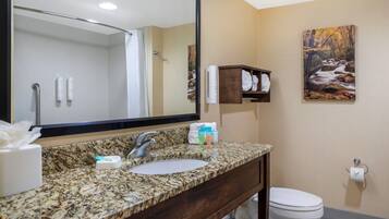 A bathroom with a granite countertop, a sink, a mirror, a towel rack, and a toilet.