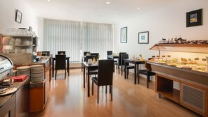 Un espace repas avec plusieurs tables et chaises, un buffet proposant divers plats, et un coin café équipé d’une machine à café et de tasses.