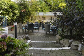 An outdoor patio area with stone paving, wicker furniture, and potted plants. - Garden Bilk Hafen (Düsseldorf)