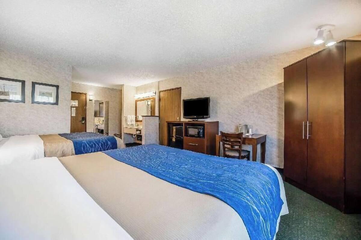 A hotel room with two beds, a desk, a television, and a wardrobe.