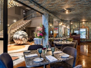 Un restaurante con mesas de mármol, una esfera decorativa grande y una escalera.