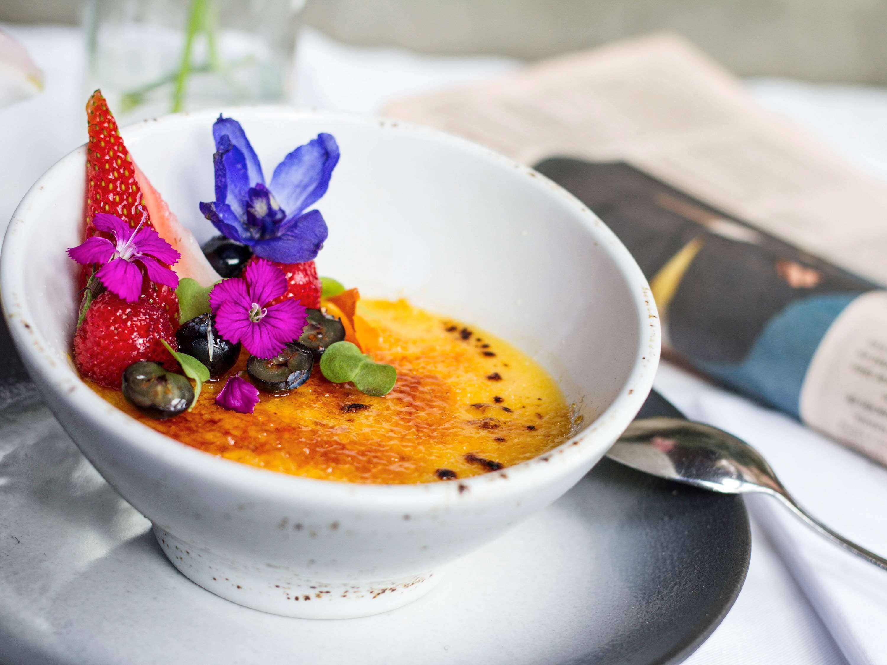 Un dessert in una ciotola bianca, con fragole, fiori e semi sopra.
