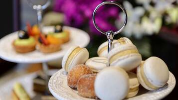 Una presentación de postres con macarons y otros dulces sobre platos blancos.