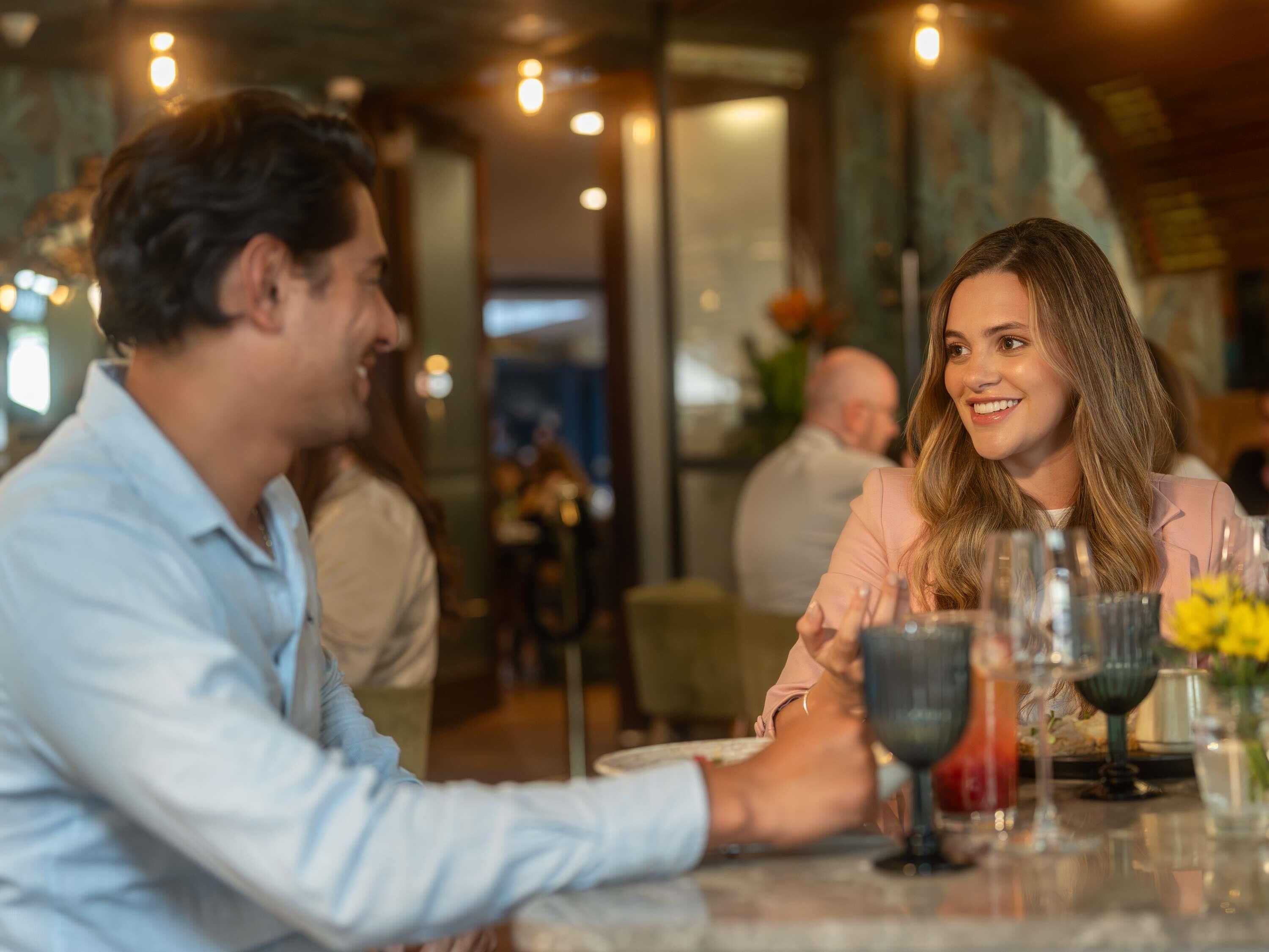 Un couple est assis à une table dans un restaurant au décor moderne et à l’éclairage d’ambiance.