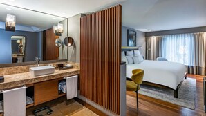 A modern hotel room with a large bed, a vanity with a mirror, and a wooden panel divider. - Sofitel Bogota Victoria Regia (Bogotá)