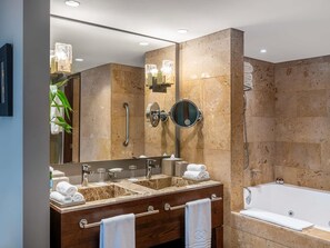 Une salle de bain moderne avec un meuble-lavabo à deux vasques, un grand miroir, un miroir rond, une douchette à main et une baignoire.