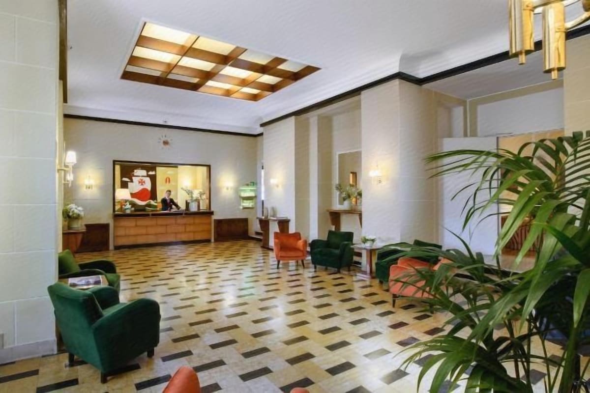 A hotel lobby with a reception desk, seating area, and a check-in counter.
