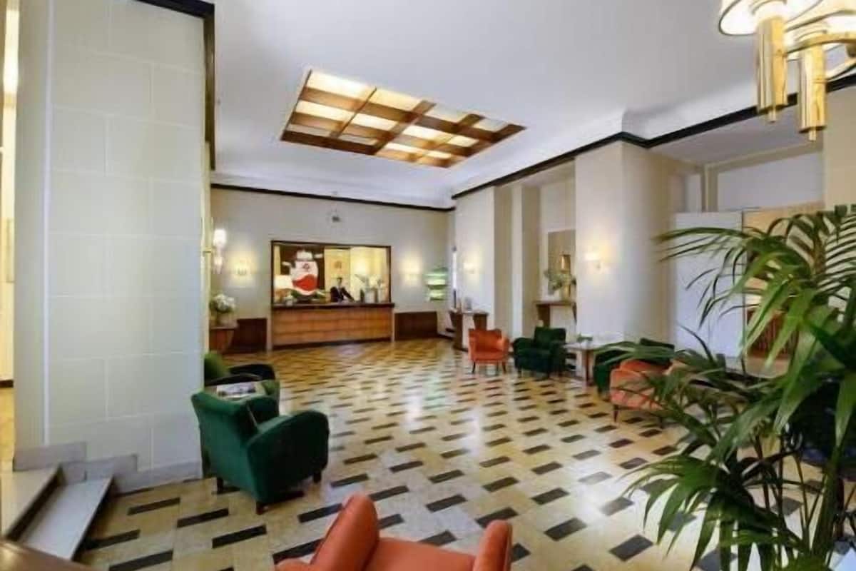A lobby with a checkered floor, a reception desk, and seating areas.