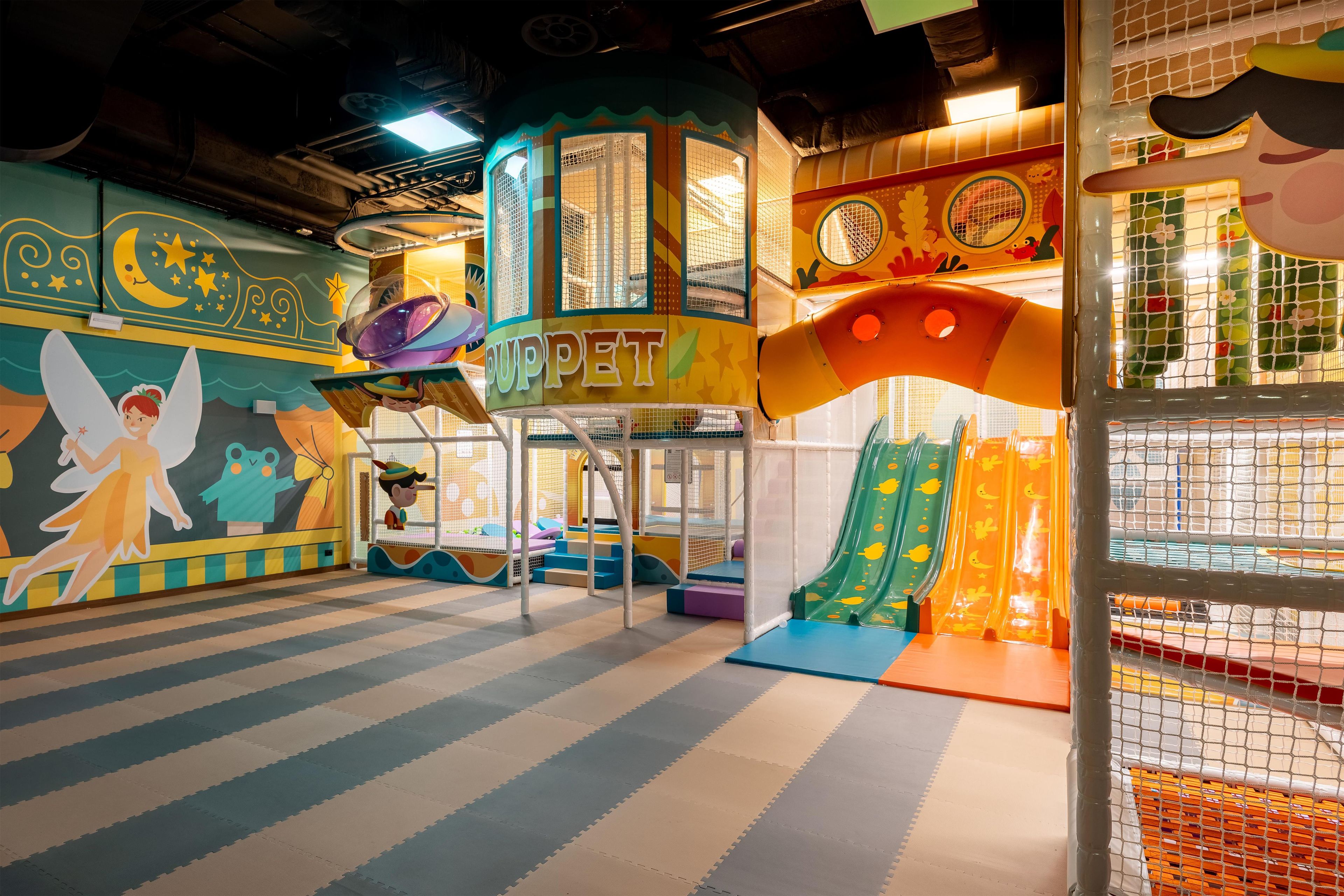 Un área de juegos infantiles con tobogán, estructuras para escalar y murales coloridos.