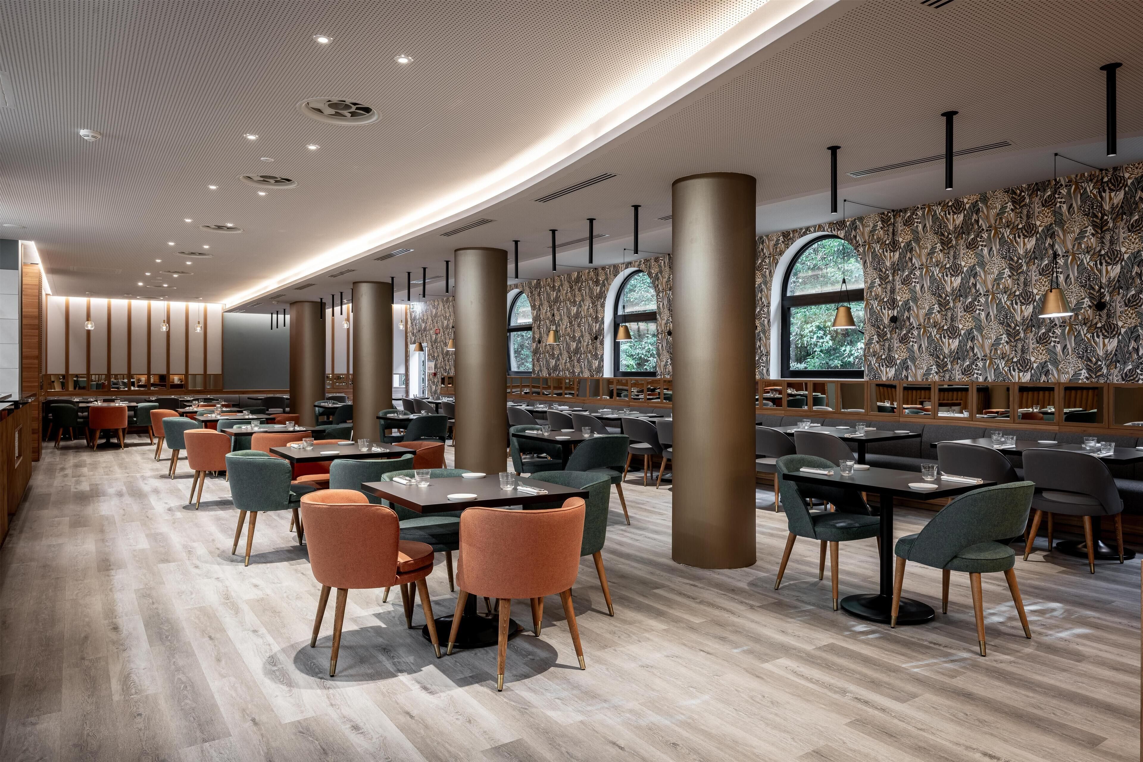 A spacious restaurant with high ceilings, modern lighting, and a patterned wall.