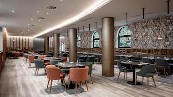 A spacious restaurant with high ceilings, modern lighting, and a patterned wall.