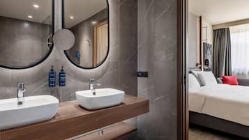 Un baño moderno con dos lavamanos, un espejo grande y un mueble de tocador de madera.