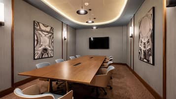A conference room with a long table, chairs, a flat-screen TV, and artwork on the walls.