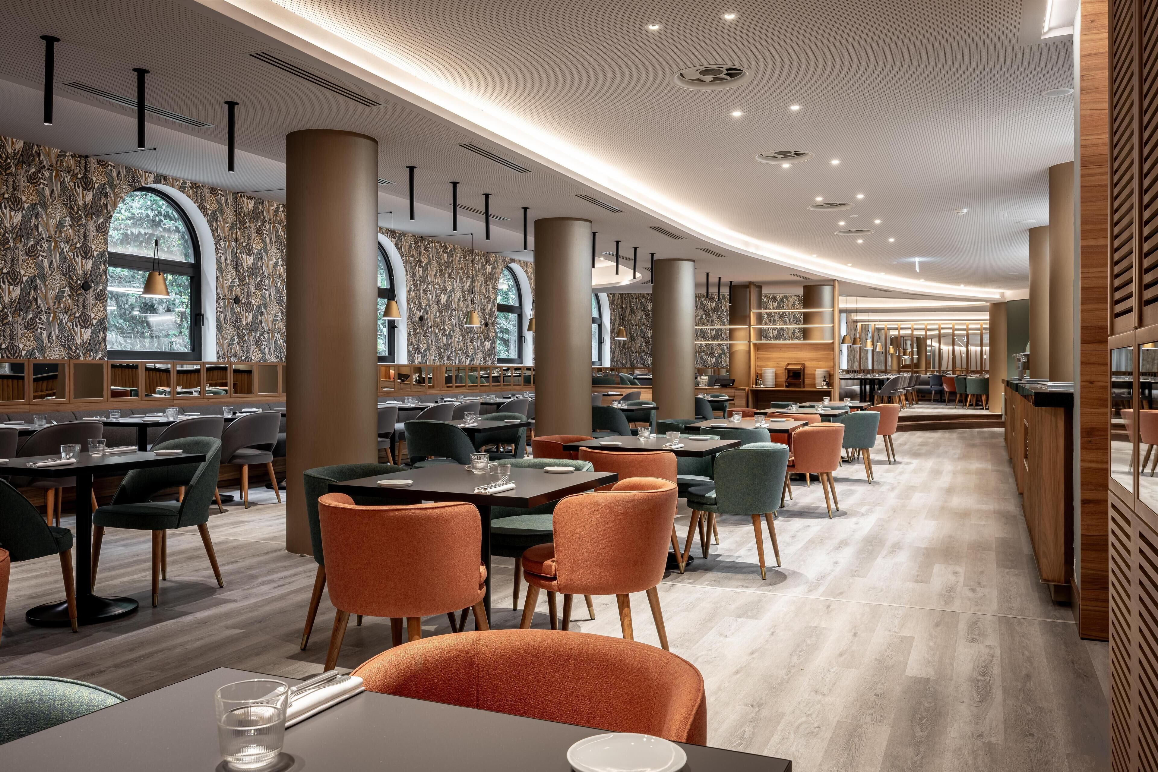 Un restaurante espacioso con techos altos, iluminación moderna y diversas opciones de asientos.