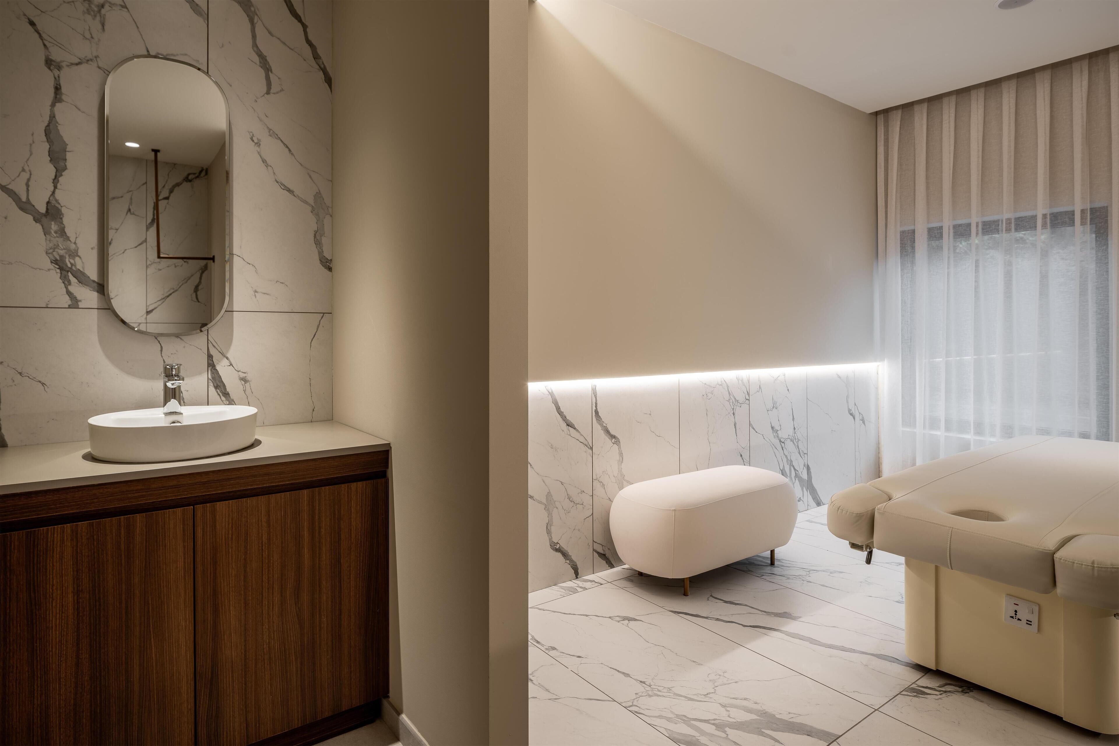 A modern bathroom with a marble vanity, a large mirror, and a massage chair.