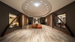 Un interior espacioso con techo alto, una zona de estar central y ventanas grandes a ambos lados.