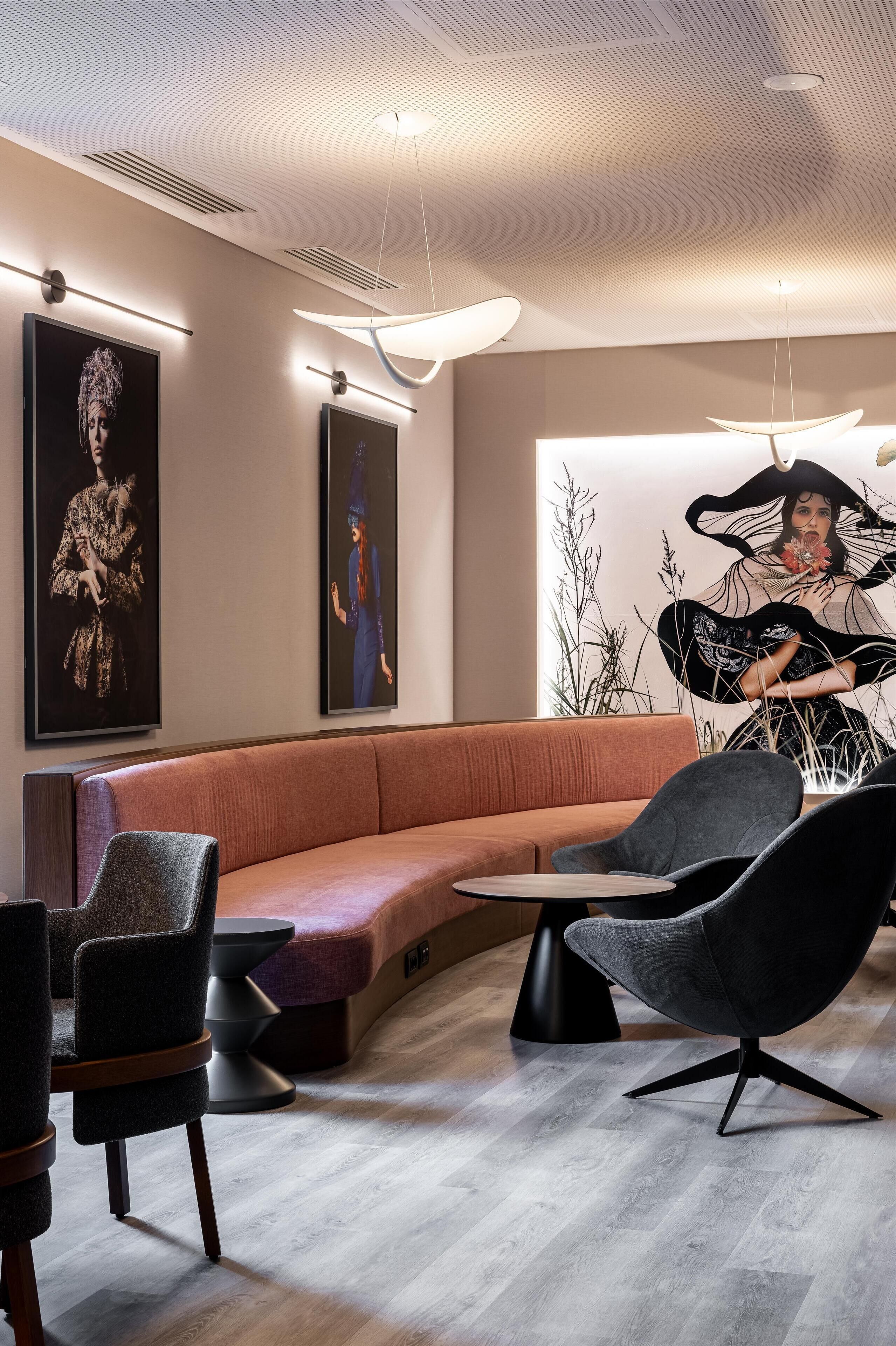 Een moderne zithoek met een gebogen bank, zwarte stoelen en een ronde tafel.