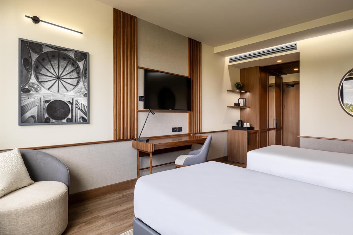 Une chambre d’hôtel équipée d’un lit, d’un bureau, d’une chaise, d’une télévision et d’une œuvre d’art accrochée au mur.