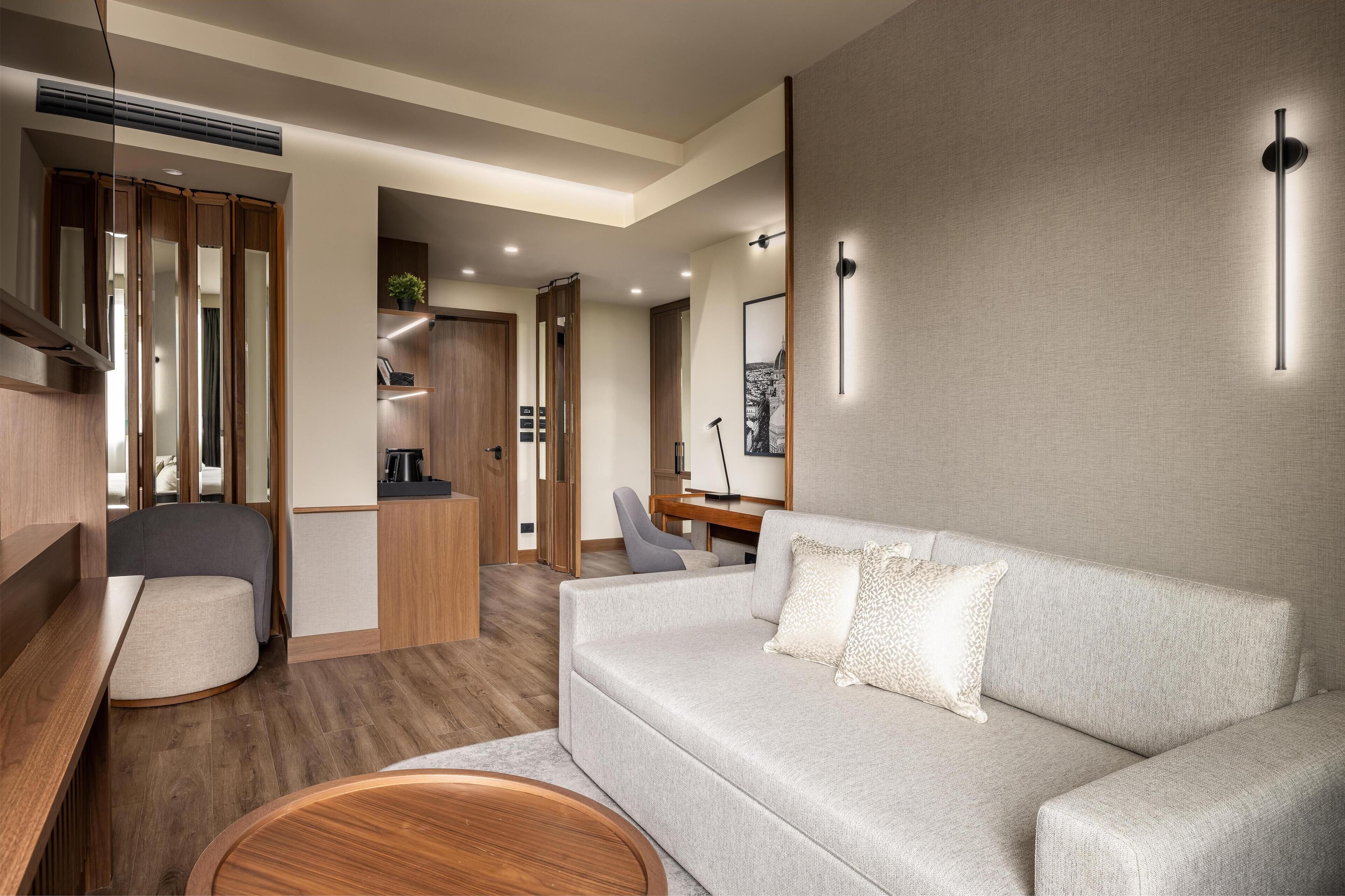 Een modern interieur met een bank, een ronde houten tafel, een bureau en een stoel.