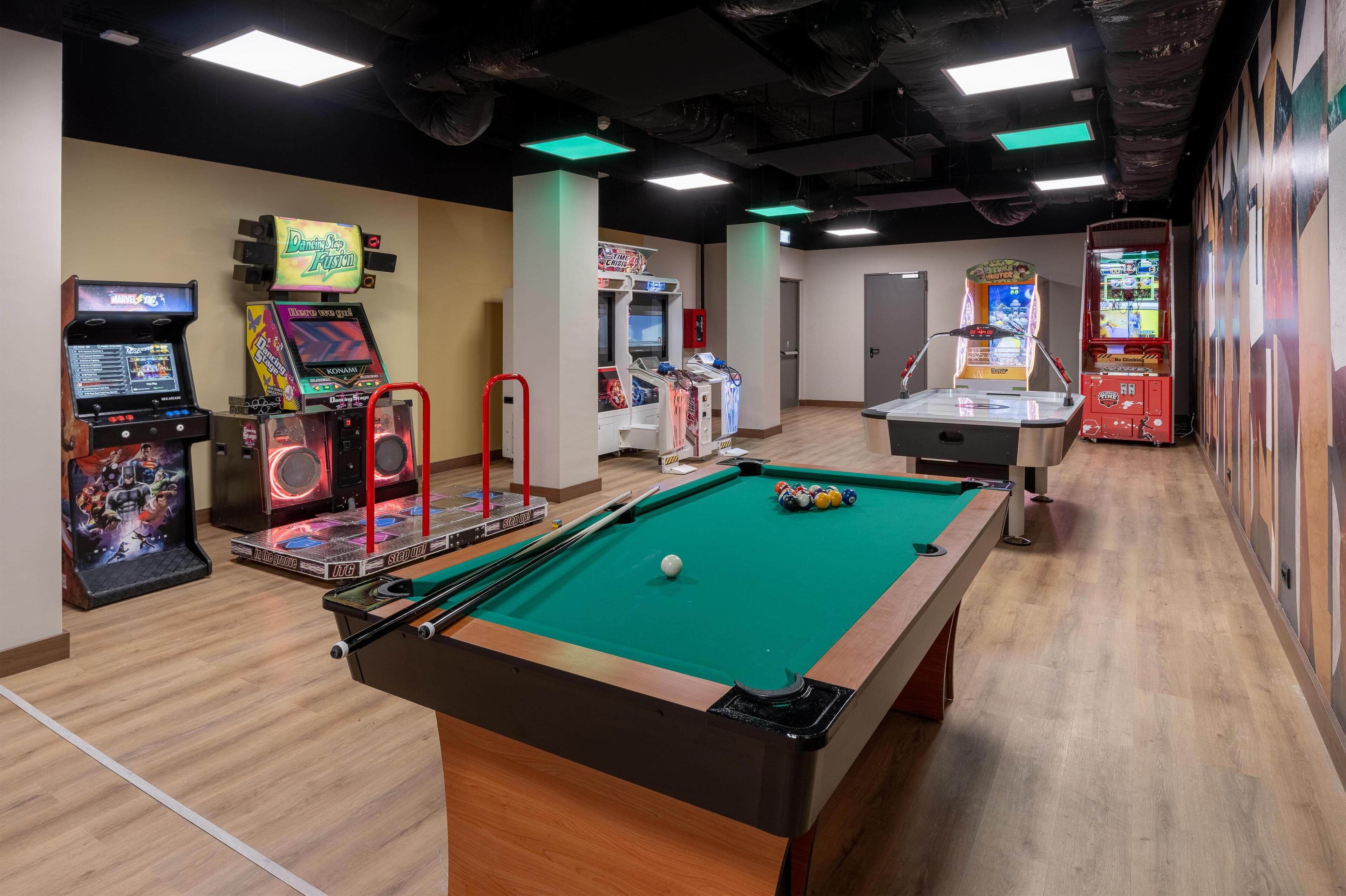 Een pooltafel met een groen vilt oppervlak, omringd door speelautomaten en een biljarttafel.
