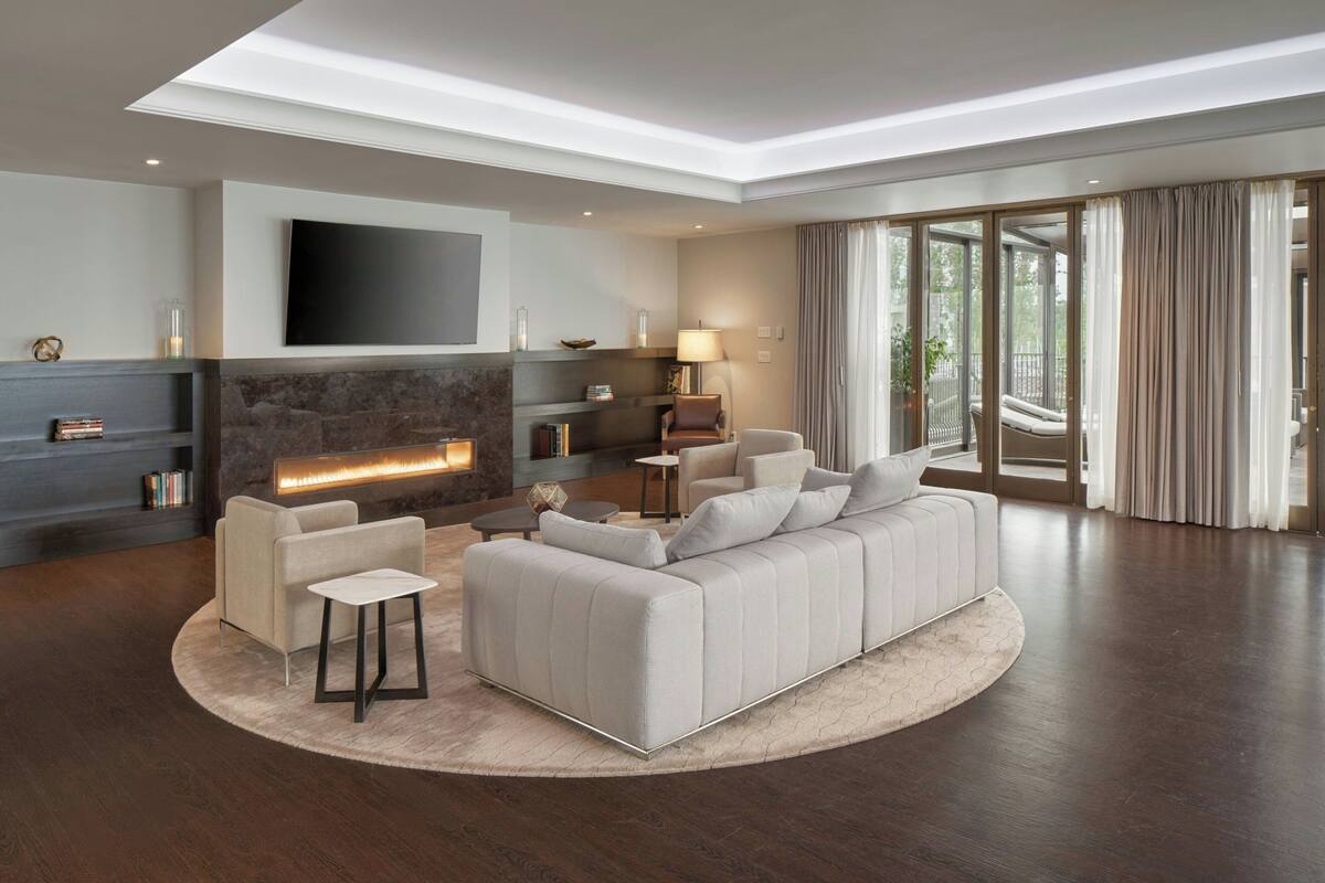 A modern living room with a fireplace, sofa, armchairs, and a TV.