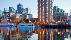 Un hôtel situé au bord de l’eau, composé de plusieurs immeubles de grande hauteur, doté d’un quai avec des bateaux et offrant une vue dégagée sur les gratte-ciel de la ville.