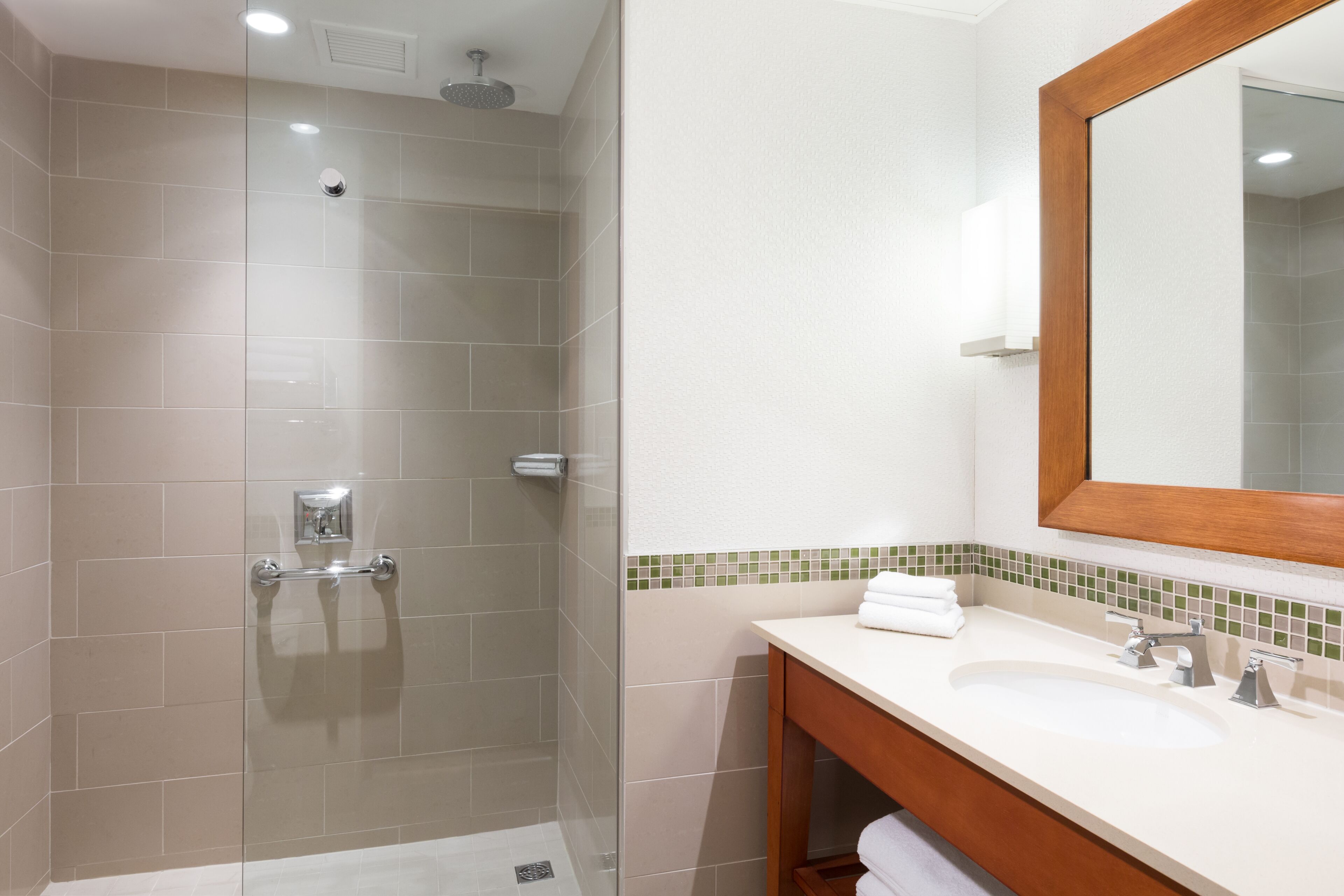 Une salle de bain moderne avec une douche à parois de verre, un meuble-lavabo en bois et un miroir.