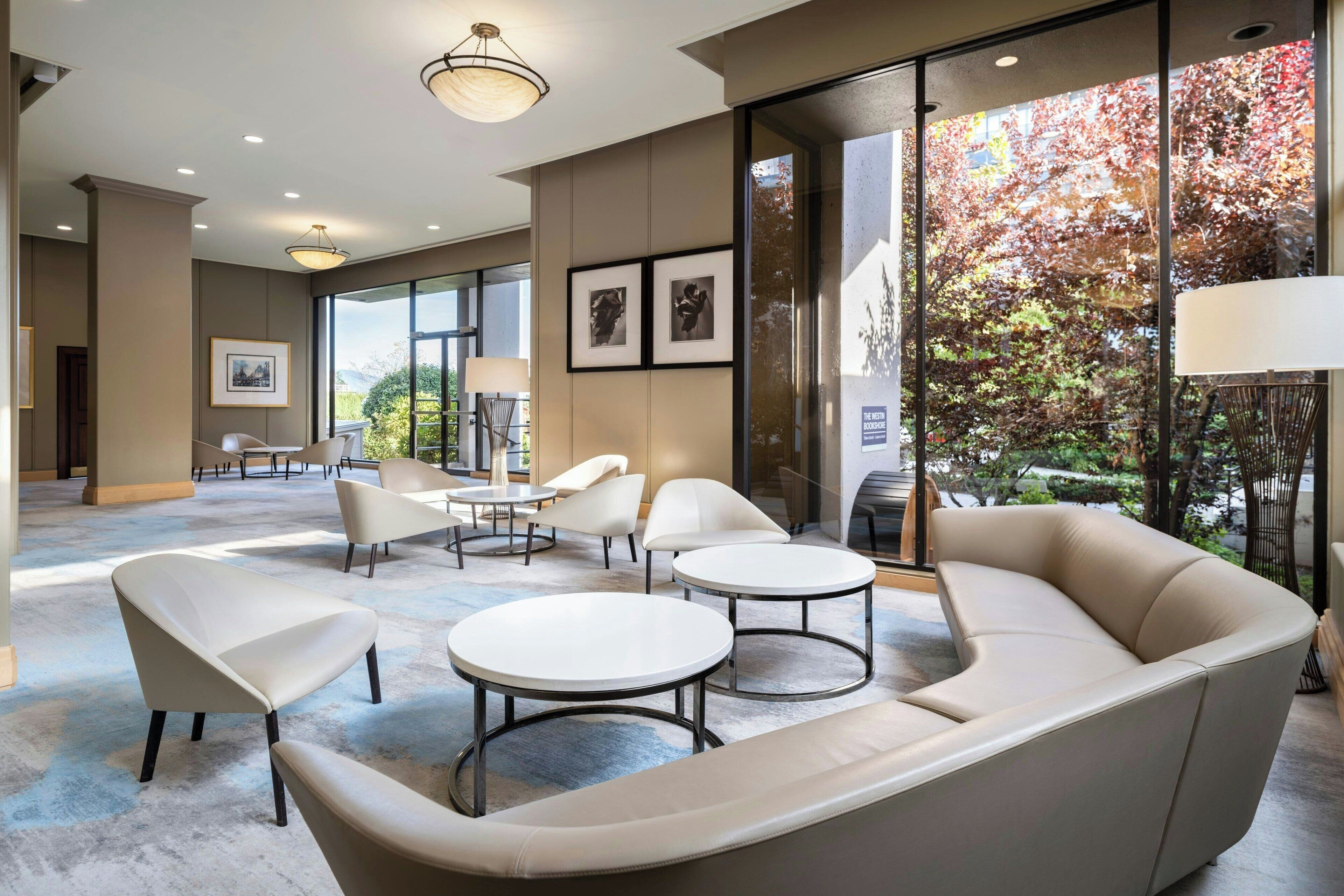 A modern lounge area with a sofa, two round tables, and several chairs.