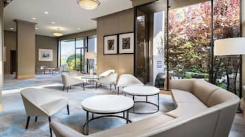 A modern lounge area with a sofa, two round tables, and several chairs.