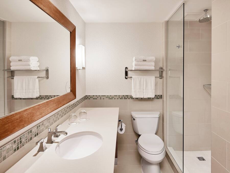 A modern bathroom with a large mirror, a sink, a toilet, and a glass-enclosed shower.