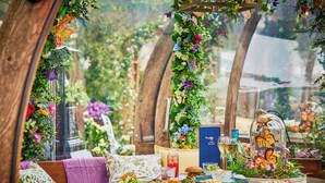 Un espace repas avec une table mise pour le repas, entouré de verdure et de fleurs.