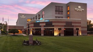 Un hotel DoubleTree by Hilton con un letrero que dice 'Shade Grill', un césped cuidado y un cielo despejado al anochecer.