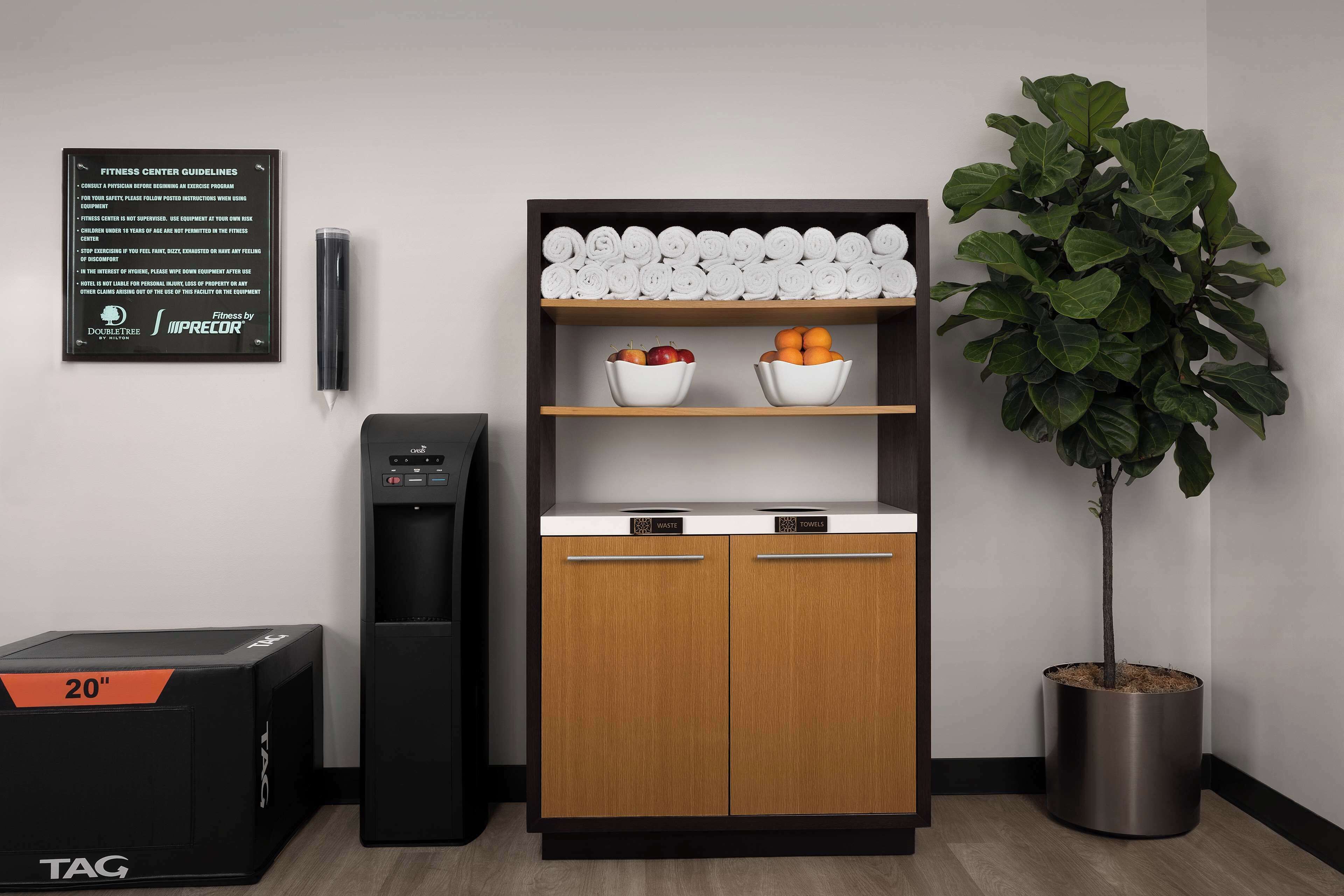 A modern kitchen with a built-in water dispenser, a wooden cabinet with a towel rack, and a potted plant.
