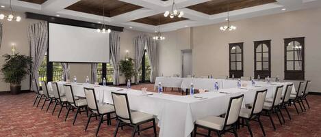 A conference room with a long table, chairs, and a projector screen.