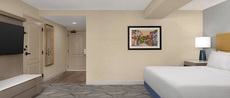 A hotel room with a bed, bedside table, lamp, and a framed picture on the wall.