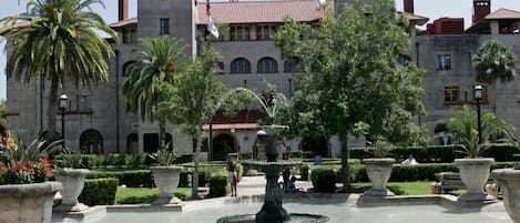 Un edificio storico con due torri, una fontana centrale e giardini curati.