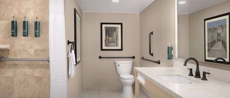 A modern bathroom with a bathtub, a toilet, and a sink with a large mirror.