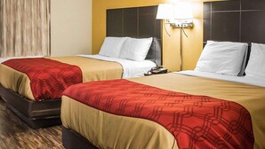A hotel room with two beds, each with a red and beige bedspread, a nightstand with a lamp, and a window with curtains. - Econo Lodge Columbus West (Columbus)