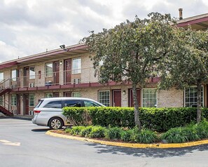 Un motel su due piani con un parcheggio e un albero di fronte.