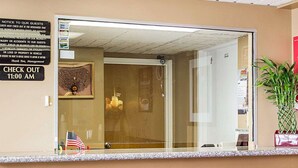 A reception area with a glass door, a sign indicating check-out time, and a small American flag. - Econo Lodge Columbus West (Columbus)