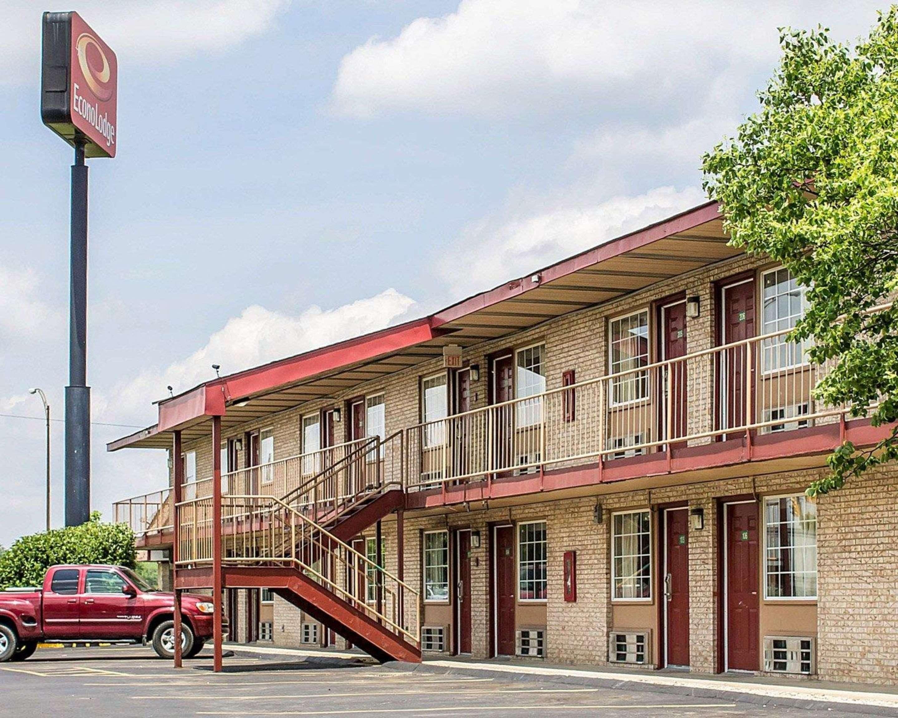 A motel with a red exterior, multiple windows, and a staircase leading to the entrance.