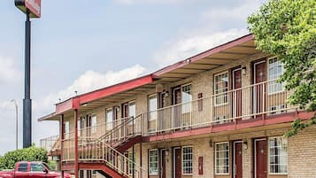 A motel with a red exterior, multiple windows, and a staircase leading to the entrance.